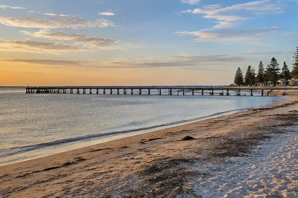 Long timber jetty beside a sandy beach at golden hour