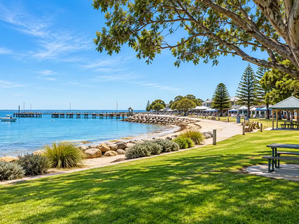 Grassy foreshore with picnic tables, beach and jetty
