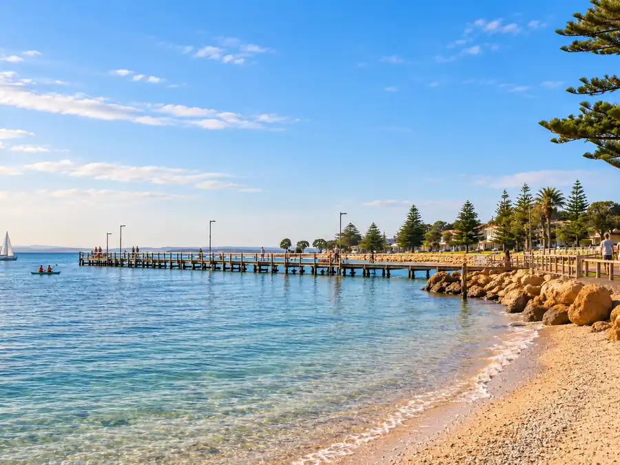 Long timber jetty beside a calm beach and foreshore