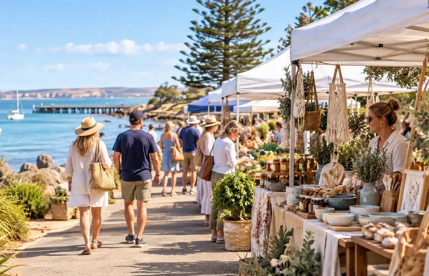 Outdoor seaside market stalls beside a calm blue bay