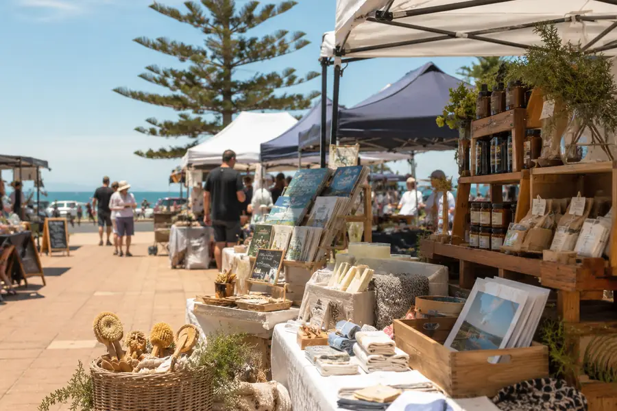 Seaside market stalls with local gifts, produce and shoppers near the foreshore