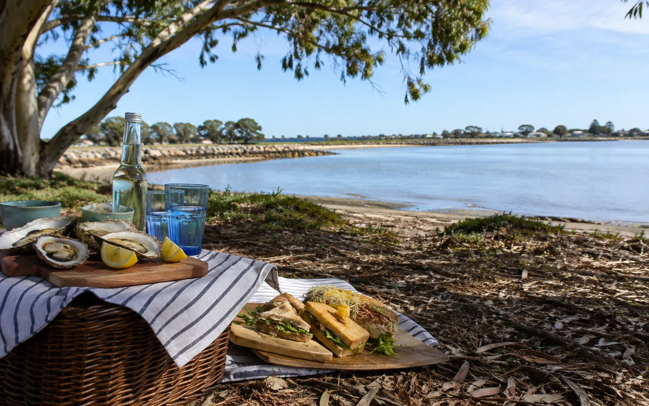 Picnic with oysters and sandwiches beside a quiet coastal bay