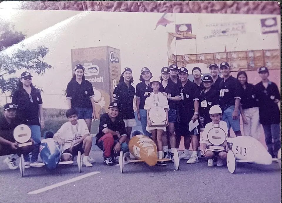Young soap box derby racers with their cars and event crew